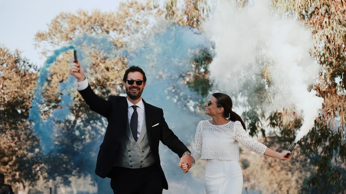 Una pareja celebrando entre humo de colores